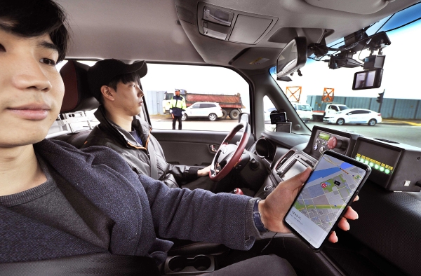 체험단이 자율주행으로 운행 중인 SK텔레콤-연세대 차량(레이) 안에서 목적지까지 경로를 스마트폰으로 확인하고 있다.