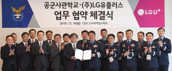 최택진 LG유플러스 기업부문장(가운데 좌측)과 박인호 공군사관학교장(가운데 우측)이 서명을 마친 업무협약서를 들고 있다.