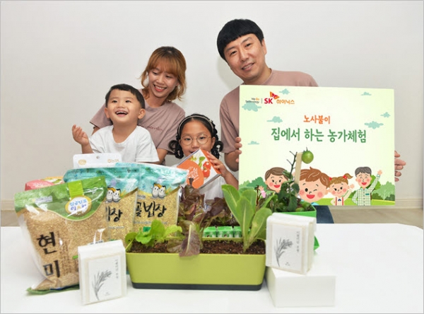 SK하이닉스 장윤숙 기장(이천FAB제조팀) 가족이 노사불이 '집에서 하는 농가 체험 박스'를 전달받고 환하게 웃고 있다.