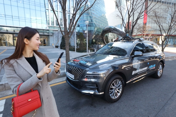 LG유플러스 모델이 서울시 상암 5G 자율주행 시범지구에서 모바일 앱으로 5G 자율주행차 'A1'을 인근 주차장으로 보내고 있다.