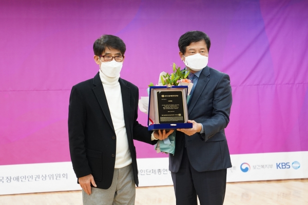 SK텔레콤 박용주 ESG 담당(오른쪽)이 한국장애인단체총연맹 변승일 공동대표에게 한국장애인인권상을 수상하고 기념촬영을 하고 있다.